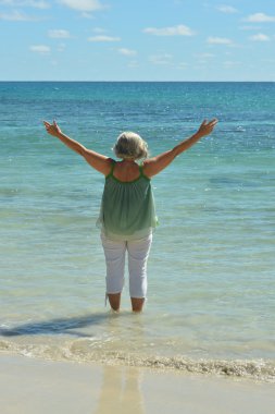 Happy elderly woman on beach clipart