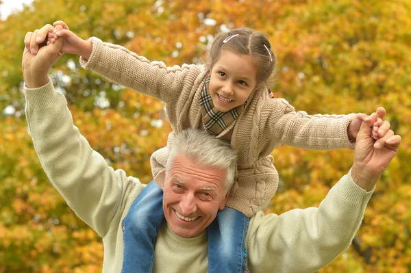 Man med barnbarn i höst park — Stockfoto