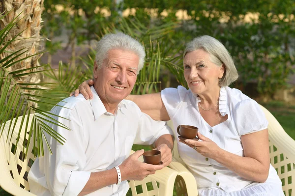 Seniorenpaar mit Kaffee im tropischen Garten — Stockfoto