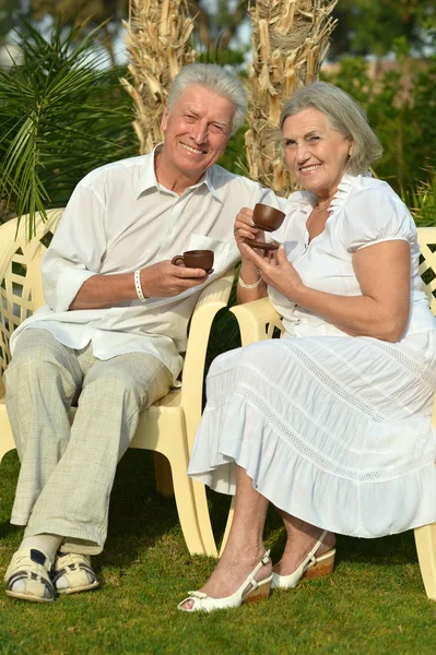 Senior couple  with coffee in tropical garden — Stock Photo, Image