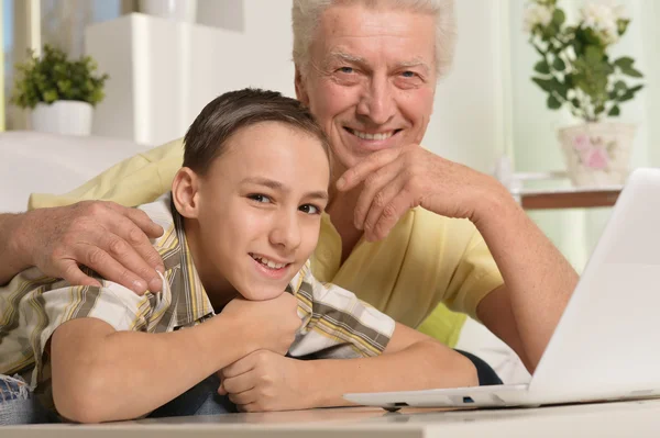 Jongen en grootvader met laptop — Stockfoto