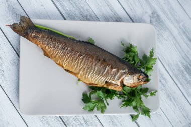 Maydanozlu füme alabalık. Tabakta füme balık, beyaz tabakta ahşap arka planda.