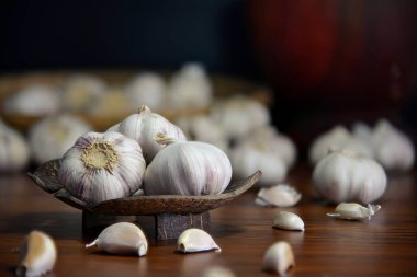 Tahta masaya konmuş hindistan cevizi kabuklarından yapılmış sarımsağın yakın plan çekimi. Loş aydınlatılmış mutfakta yemek malzemeleri için hazırlanıyor..