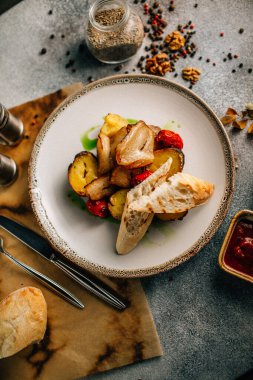 Kızarmış et, patates ve sebzeyle birlikte beyaz tabakta ekmek, yakın görüş 