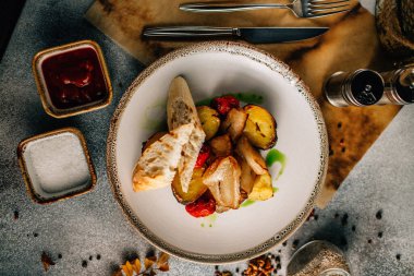 Kızarmış et, patates ve sebzeyle birlikte beyaz tabakta ekmek, yakın görüş 