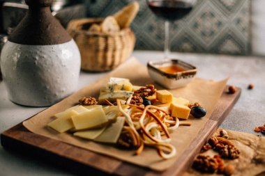 Tahtada peynir tabağı, üzümlü ve fındıklı, masada bal, yakın görüş. 