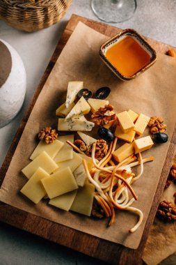Tahtada peynir tabağı, üzümlü ve fındıklı, masada bal, yakın görüş. 
