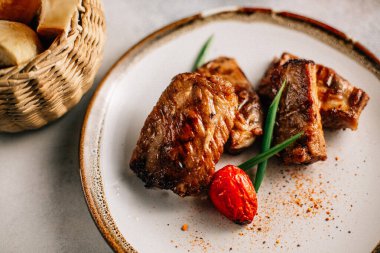 Yeşil soğanlı ızgara balık bifteği ve tabakta domates, kasede ekmek, üst manzara.