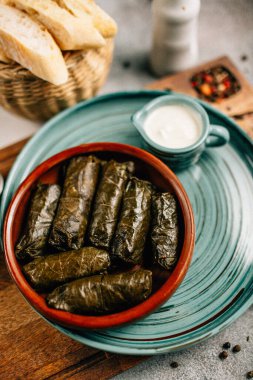 Tahta kesim tahtası ve ekmek üzerine dolma ve sos tabağı, yakın görüş.