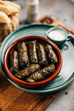 Tahta kesim tahtası ve ekmek üzerine dolma ve sos tabağı, yakın görüş.