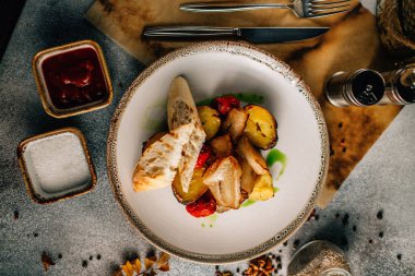 Kızarmış et, patates ve sebzeyle birlikte beyaz tabakta ekmek, yakın görüş 