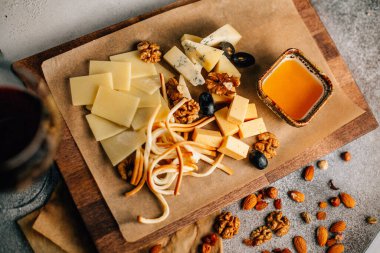 Tahtada peynir tabağı, üzümlü ve fındıklı, masada bal, yakın görüş. 