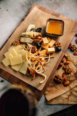Tahtada peynir tabağı, üzümlü ve fındıklı, masada bal, yakın görüş. 