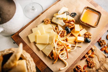 Tahtada peynir tabağı, üzümlü ve fındıklı, masada bal, yakın görüş. 