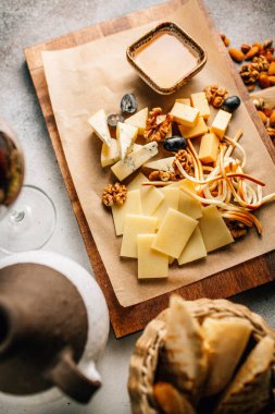 Tahtada peynir tabağı, üzümlü ve fındıklı, masada bal, yakın görüş. 