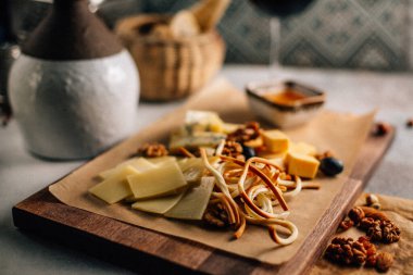 Tahtada peynir tabağı, üzümlü ve fındıklı, masada bal, yakın görüş. 