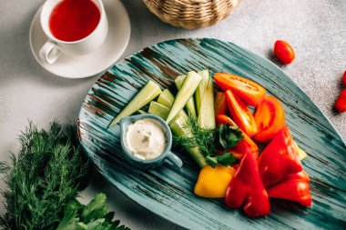 Taze kesilmiş sebze tabağı ve masada çay fincanı ile sos, yakın görüş. 
