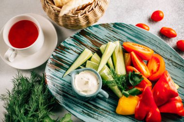 Taze doğranmış sebze ve soslu ekmek sepeti ve masada çay fincanı, yakın görüş. 
