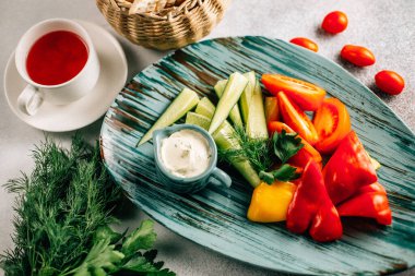 Taze doğranmış sebze ve soslu ekmek sepeti ve masada çay fincanı, yakın görüş. 