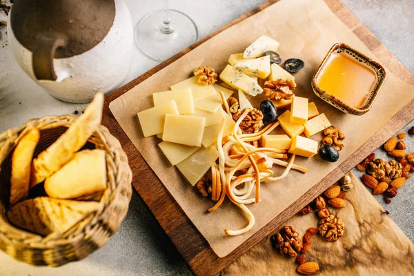Tahtada peynir tabağı, üzümlü ve fındıklı, masada bal, yakın görüş. 