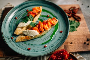 Mini bruschetta tabağı ve yumuşak mascarpone peynirli somon ve ahşap kesim tahtasının üzerinde nar tohumları. 