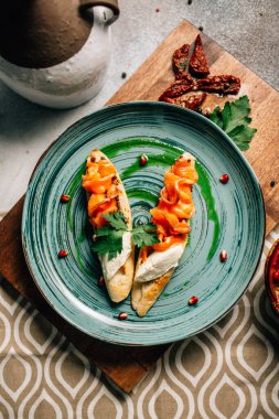 Mini bruschetta tabağı ve yumuşak mascarpone peynirli somon ve ahşap kesim tahtasının üzerinde nar tohumları. 