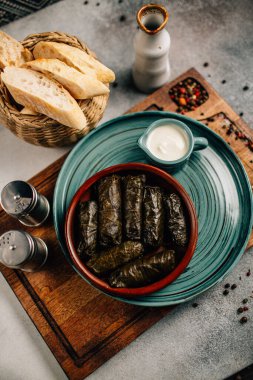 Tahta kesim tahtası ve ekmek üzerine dolma ve sos tabağı, yakın görüş.