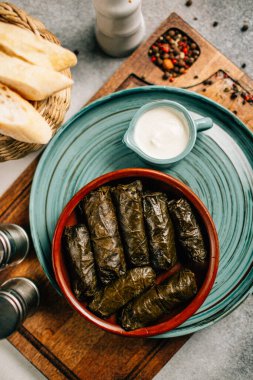 Tahta kesim tahtası ve ekmek üzerine dolma ve sos tabağı, yakın görüş.