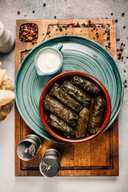 Tahta kesim tahtası ve ekmek üzerine dolma ve sos tabağı, yakın görüş.