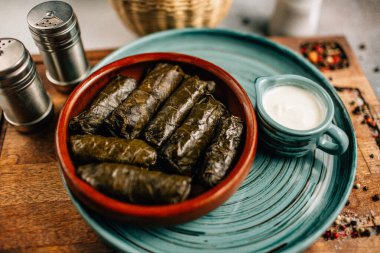 Ahşap kesme tahtasının üzerinde dolma ve sos tabağı, yakın görüş.