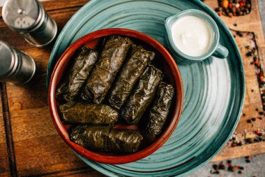 Ahşap kesme tahtasının üzerinde dolma ve sos tabağı, yakın görüş.