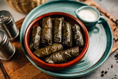 Ahşap kesme tahtasının üzerinde dolma ve sos tabağı, yakın görüş.