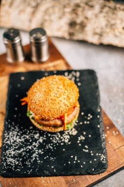 Koyu taş tabakta taze lezzetli bir hamburger, yakın görüş. 
