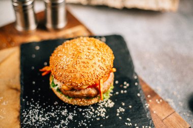 Koyu taş tabakta taze lezzetli bir hamburger, yakın görüş. 