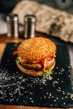 Koyu taş tabakta taze lezzetli bir hamburger, yakın görüş. 