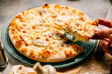 Masadaki tabaktan bir dilim Megrelian Khachapuri alan erkek eli, yakın görüş. 