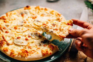 Masadaki tabaktan bir dilim Megrelian Khachapuri alan erkek eli, yakın görüş. 