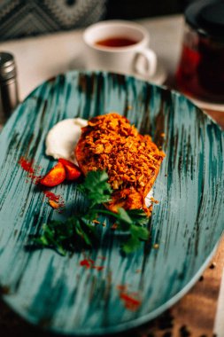 Lezzetli kızarmış et ve ekşi krema soslu vişneli domates ve bir fincan çay ve çaydanlık ile maydanoz. 