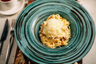 Peynirli makarna masada çay fincanının yanında.
