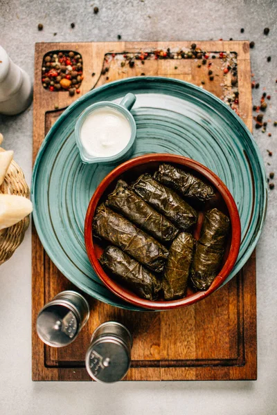 Tahta kesim tahtası ve ekmek üzerine dolma ve sos tabağı, yakın görüş.