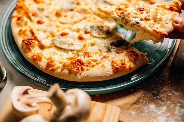 Masadaki tabaktan bir dilim Megrelian Khachapuri alan erkek eli, yakın görüş. 