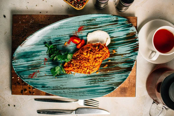 Lezzetli kızarmış et ve ekşi krema soslu vişneli domates ve bir fincan çay ve çaydanlık ile maydanoz. 