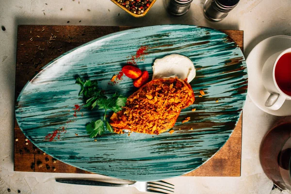 Lezzetli kızarmış et ve ekşi krema soslu vişneli domates ve bir fincan çay ve çaydanlık ile maydanoz. 