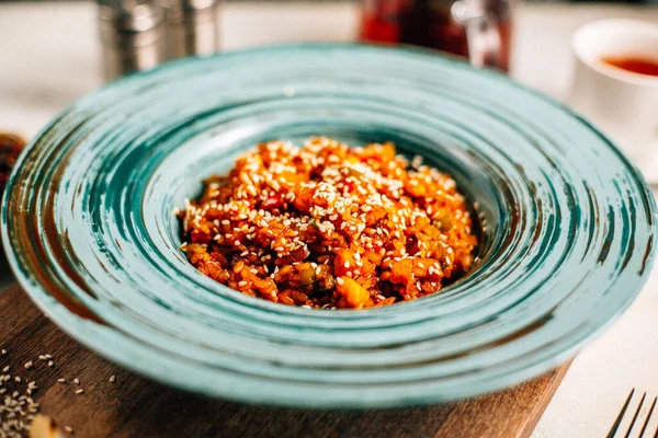 Sebze yahnili tabak ve tahtadan kesme tahtasına susam tohumlu yulaf ezmesi, yakın görüş. 