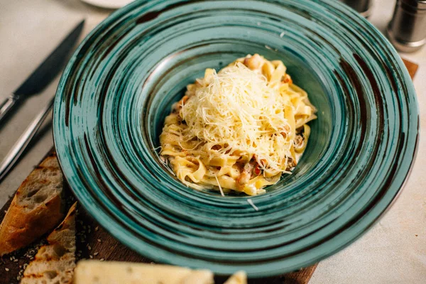 Peynirli makarna tabakta ve masada ekmek