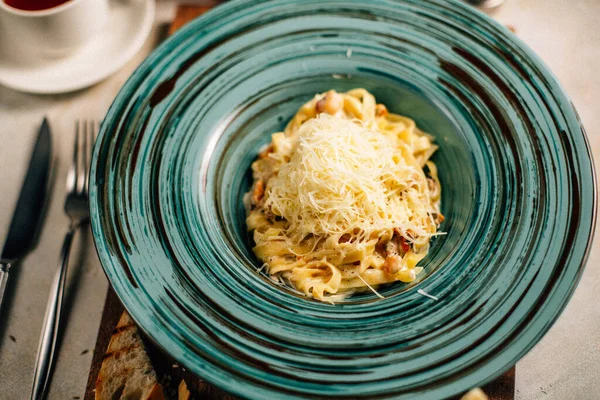 Peynirli makarna masada çay fincanının yanında.
