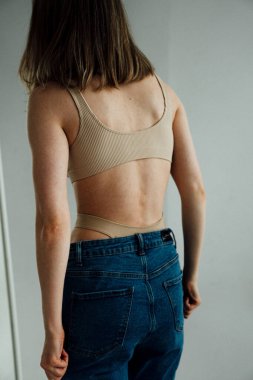 Spor iç çamaşırı giyen ve ışık stüdyosunda poz veren güzel bir kızın arka plan görüntüsü. 