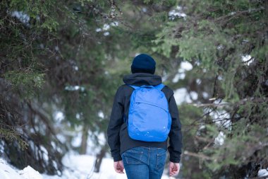 Genç bir adam ormanda güzel bir kış gününde patika boyunca yürür..