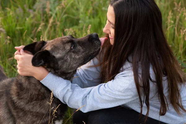 Doğada kahverengi köpeği olan mutlu genç bir kadın.
