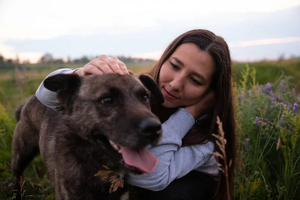 Doğada kahverengi köpeği olan mutlu genç bir kadın.